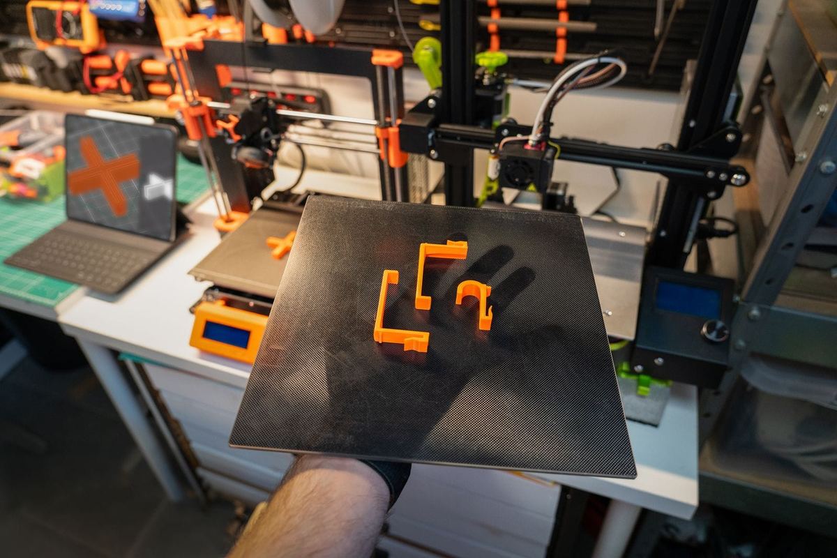 Druckplatte mit frisch gedruckten orangen Kunststoffteilen